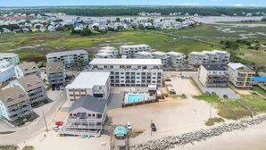A coastal hotel with multiple buildings, a swimming pool, and a beach area. - Beach, You Crazy! by Carolina Getaway- Oceanfront 2BR Condo POOL & HOT TUB OPEN (Carolina Beach)