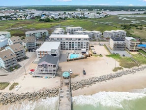 Un hôtel situé sur la côte, composé de plusieurs bâtiments, doté d’une piscine et d’un espace de plage.