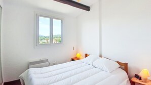 Une chambre à coucher avec un lit, une fenêtre, un radiateur et une table de chevet avec une lampe.