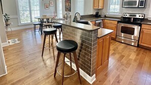 A spacious kitchen with a central island, wooden cabinets, stainless steel appliances, and a ceiling fan. - Spacious 4 Bed Island House on Lake Hamilton with Boat Slip (Hot Springs)