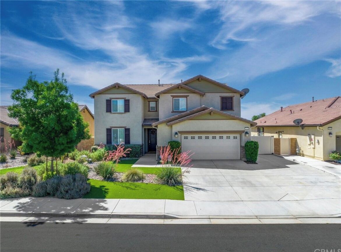 A two-story house with a garage, a well-maintained lawn, and a clear blue sky.