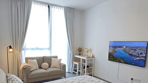 Ein Schlafzimmer mit einem großen Bett, einem Schreibtisch, einem Sessel, einem Globus und einem Fernseher an der Wand.