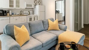 Un salon moderne avec un canapé d’angle bleu clair, une table basse ronde et un ventilateur de plafond.