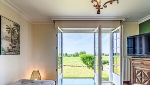 A room with a large window, a sofa, a television, and a painting of leopards. - Villa Colette by Interhome (Plouhinec Morbihan)