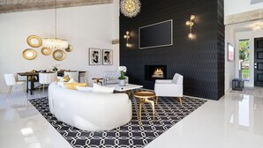 Una sala de estar moderna con una pared texturizada negra, una chimenea y un comedor con una mesa y sillas blancas.