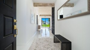 Un pasillo con una puerta negra, un banco y un espejo grande en la pared.