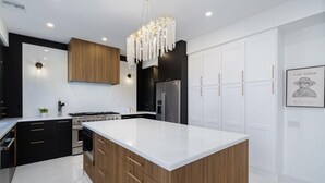 Una cocina moderna con una isla grande, electrodomésticos de acero inoxidable y una araña.