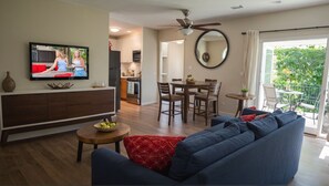 A living room with a sofa, TV, dining table, chairs, and a balcony with a view. - Executive Suites near Santa Monica (Los Angeles)
