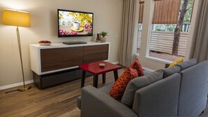 Una sala de estar moderna con un sofá, una mesita, un televisor y una lámpara.