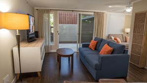 Una sala de estar con un sofá, una mesa de centro, un televisor y una lámpara.