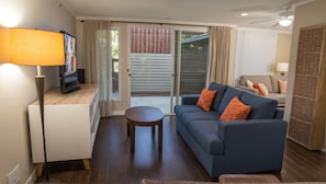 A living room with a sofa, a coffee table, a TV, and a lamp. - Executive Suites near Santa Monica (Los Angeles)
