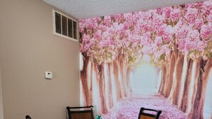 Un coin repas avec une table ronde, quatre chaises et une fresque murale représentant des fleurs de cerisier.