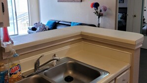 Une cuisine compacte dotée de deux éviers en acier inoxydable, d’un plan de travail et de meubles de couleur beige.