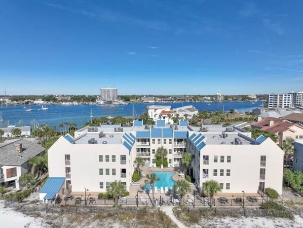 A hotel with a pool, beachfront view, and multiple buildings in the background.