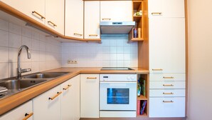 Eine kleine Küche mit weißen Schränken, einer Edelstahl-Spüle und einem eingebauten Backofen.