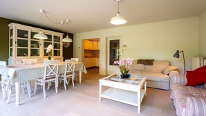 Ein Wohnzimmer mit einem weißen Sofa, einem Couchtisch und einem Essbereich mit Tisch und Stühlen.