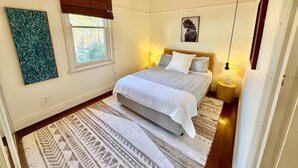 A bedroom with a bed, a window with blinds, a hanging light fixture, and a wall-mounted picture. - Cosy Manly Beach Hideaway (Manly)