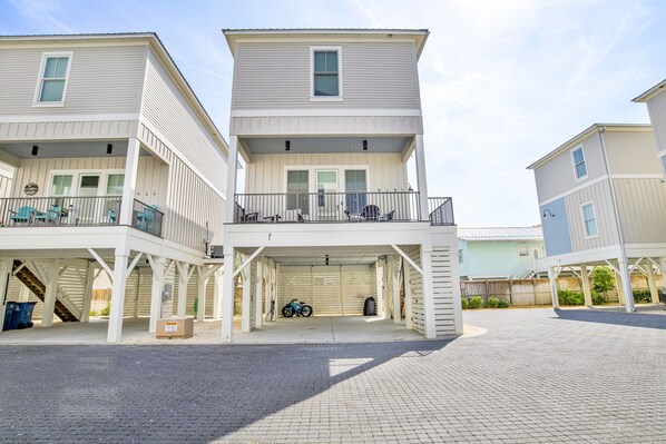 A multi-story residential building with a covered parking area and a bicycle parked inside. - 2 min to beach - BBQ | Video Games | Bikes | Pool (Gulf Shores)