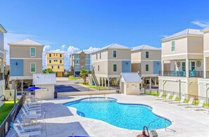 A residential building complex with a swimming pool, lounge chairs, and a small building with a roof. - 2 min to beach - BBQ | Video Games | Bikes | Pool (Gulf Shores)