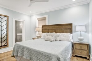 A bedroom with a large bed, a wooden headboard, a nightstand with a lamp, and a wardrobe. - 2 min to beach - BBQ | Video Games | Bikes | Pool (Gulf Shores)