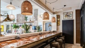 A modern bar area with a long counter, multiple hanging wicker light fixtures, and bar stools. - City Club - Unit 429 (Cincinnati)