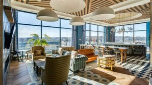 A spacious living area with large windows, a high ceiling with wooden beams, and a mix of seating including sofas and armchairs. - City Club - Unit 429 (Cincinnati)