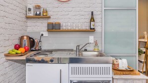 A compact kitchen with a white brick wall, a stainless steel sink, and a coffee maker.