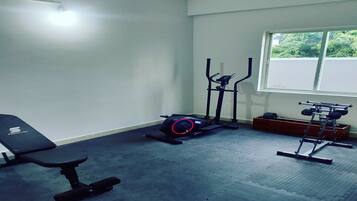A gym with a bench, elliptical, and weight machine.