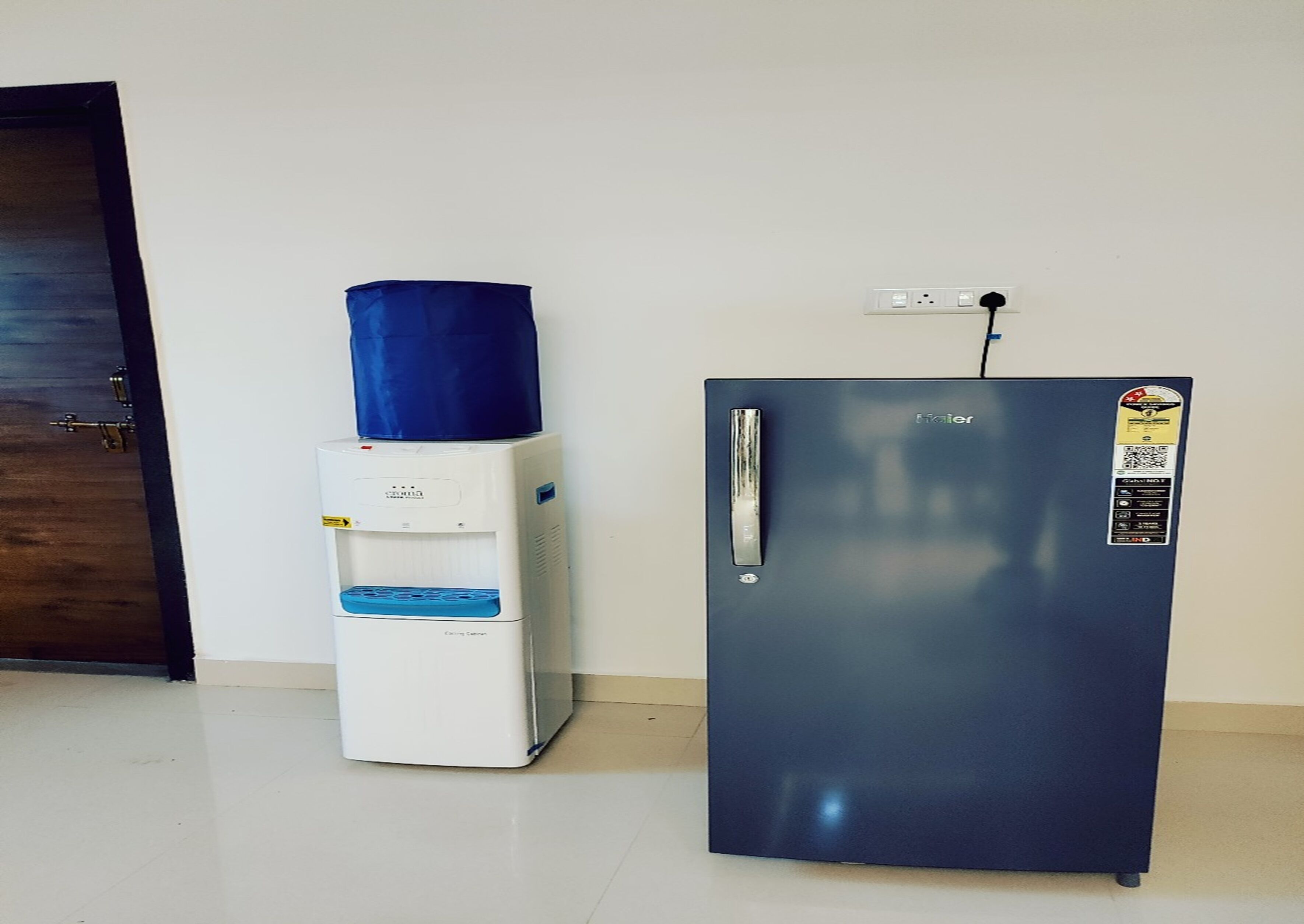 A compact kitchenette with a water dispenser and a refrigerator.