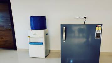 A compact kitchenette with a water dispenser and a refrigerator.