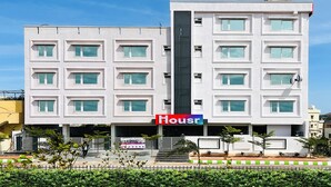 A modern multi-story building with a prominent 'Housr' sign, featuring a symmetrical facade with evenly spaced windows and a central vertical element. - Housr Rushikonda Visakhapatnam (Visakhapatnam)