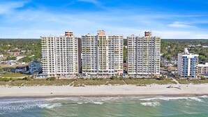 Een strandhotel met meerdere hoge gebouwen, een zandstrand en uitzicht op de oceaan.