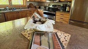 Une cuisine avec des meubles en bois, un réfrigérateur en acier inoxydable, un four à micro-ondes et une cuisinière. On y trouve un paillasson et un panneau décoratif posé sur le comptoir.