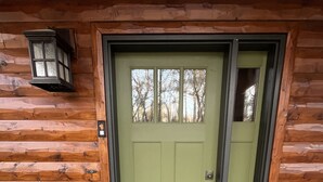 Une cabane en bois avec une porte verte et un paillasson.