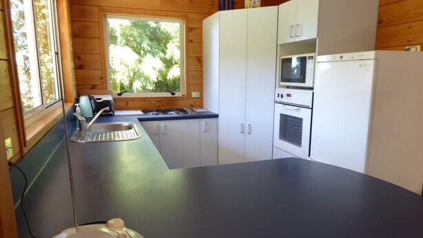 A modern kitchen with a black countertop, white cabinets, a built-in microwave, and a gas stove. - Family Cottage on Established Rural Farm. Relaxing, Secluded, has Beautiful View (Broomfield)