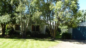A house with a front yard, a garage, and a tree in front of the house. - Family Cottage on Established Rural Farm. Relaxing, Secluded, has Beautiful View (Broomfield)