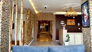 A modern hotel lobby with a bamboo wall, a reception desk, and a seating area. - Hotel Valna Estate Mountain View Kausani By HRG (Kausani)
