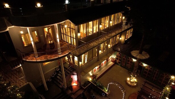 A multi-story hotel with a central courtyard, balconies, and a well-lit interior. - Hotel Valna Estate Mountain View Kausani By HRG (Kausani)