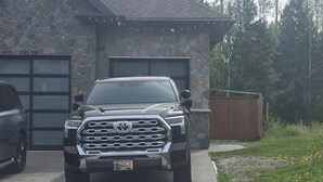 Ein Steinhaus mit Garage, Auffahrt und einem geparkten Fahrzeug davor.
