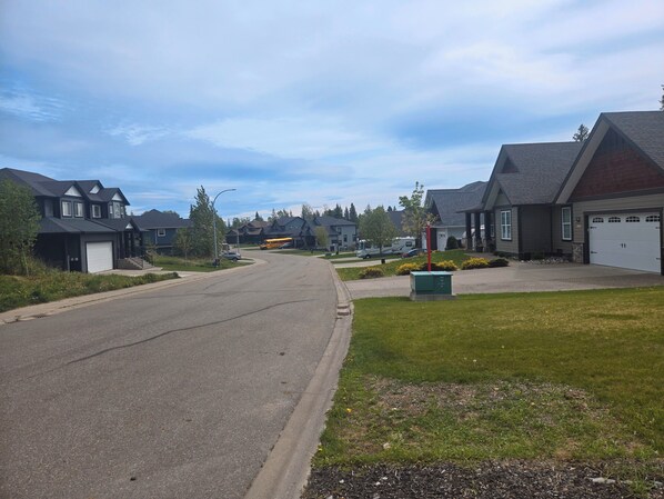 A residential street with houses, a school bus, and a clear sky.