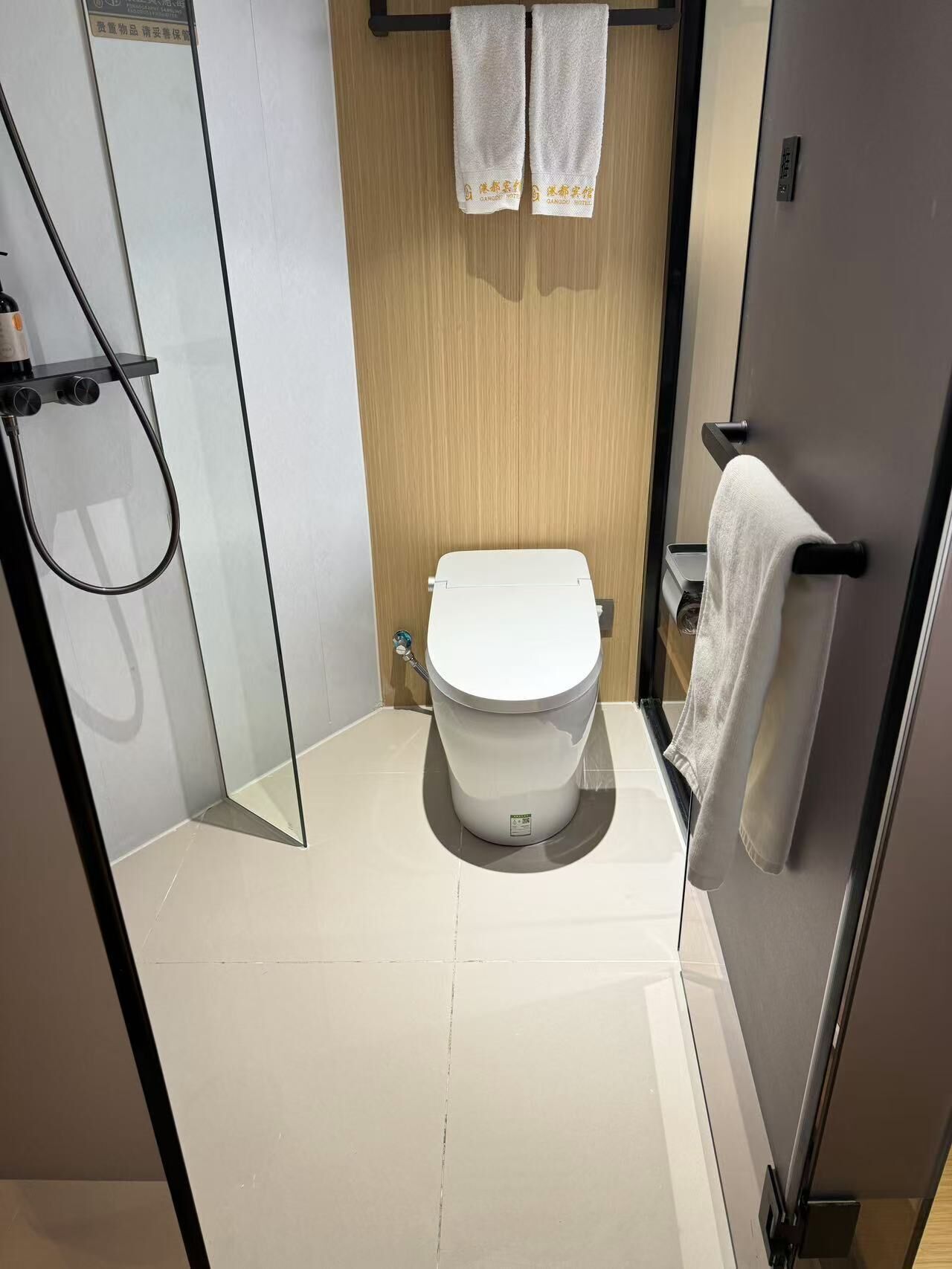 Een moderne badkamer met een douchecabine van glas, een wit toilet en een houten wastafelmeubel.