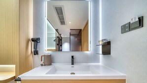 A modern bathroom with a large mirror, a white sink, and a hairdryer mounted on the wall. - gangduhotel (Shaoxing)