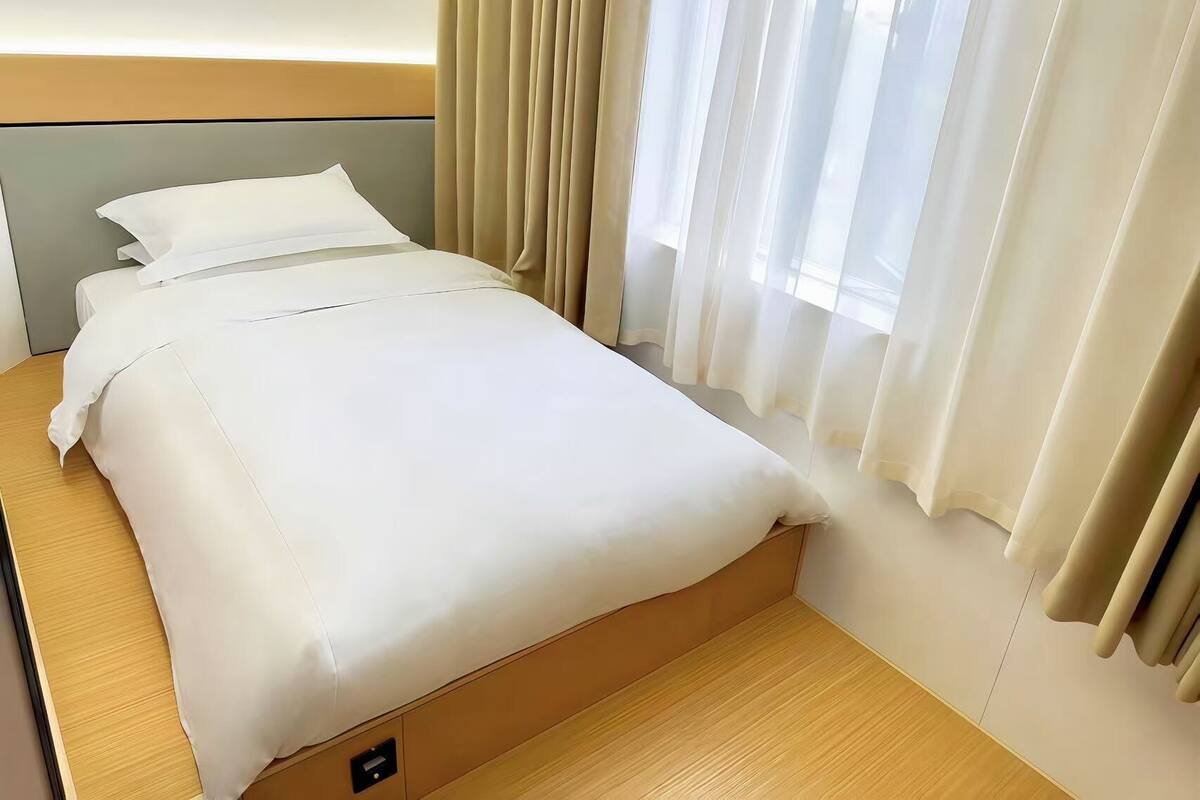 A neatly made bed with white linens in a hotel room.