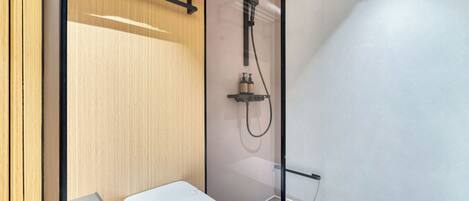 A modern bathroom with a glass shower enclosure, a towel rack, and a toilet.