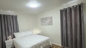 Une chambre à coucher comprenant un lit, des tables de chevet, un luminaire au plafond et une œuvre d’art accrochée au mur.