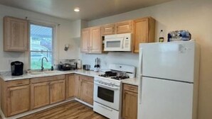 Une cuisine avec des meubles de rangement en bois, un réfrigérateur blanc, une cuisinière et un four à micro-ondes.