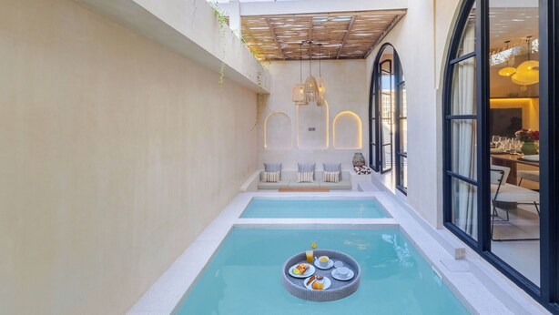 A private pool area with a dining setup and a seating area. - Villa San Miguel by Pertama Stay (Seminyak)