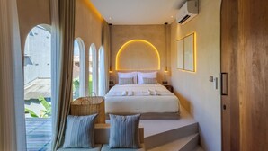 A modern hotel room with a large bed, a curved wall light, and a view of the outside. - Villa San Miguel by Pertama Stay (Seminyak)