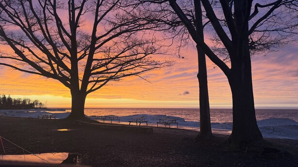 A sunset view with trees and benches along a lakeside path. - Cozy Charming house in Oswego NY, with WiFi and AC (Oswego)