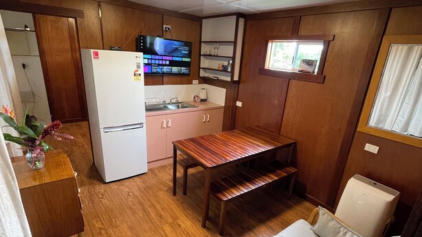 A compact kitchen with a refrigerator, a sink, and a wooden dining table. - Clean and convenient cabin Centrally located in Atherton township. (Atherton)